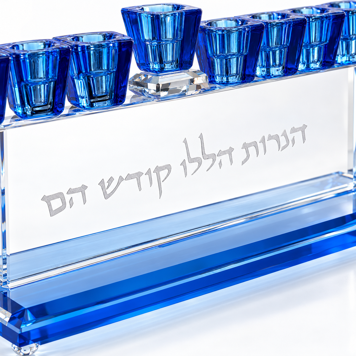 Close-up of the Hebrew engraving and blue faceted cups on a crystal Hanukkah menorah