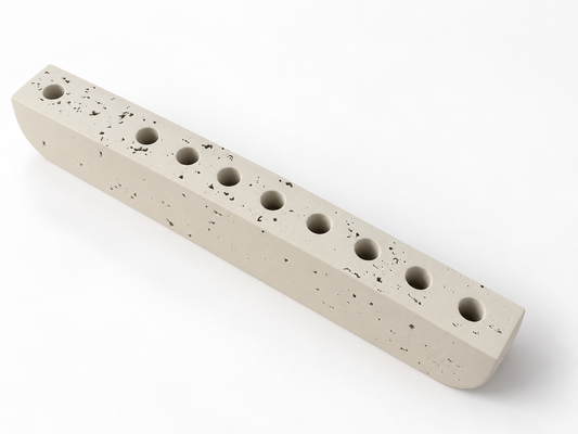 Ivory concrete hanukkiah viewed from above, showing nine recessed holders and textured surface