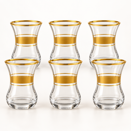 Six clear glass tea cups with gold bands on a white background