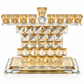 Gold geometric crystal Hanukkah menorah with amber-gold glass holders, faceted crystal body and a raised central shamash on a white background