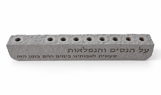 Higher angle of gray Al Hanissim concrete hanukkiah showing nine recessed holders and engraved Hebrew lettering