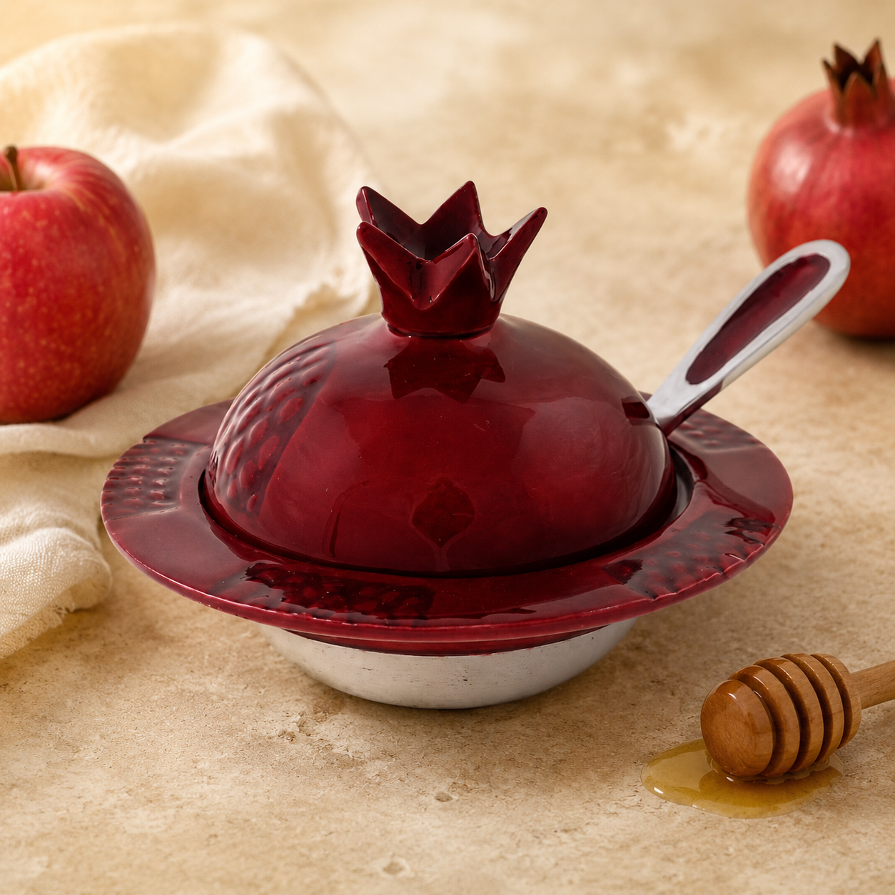 Red pomegranate honey dish with spoon staged with apples and honey for Rosh Hashanah