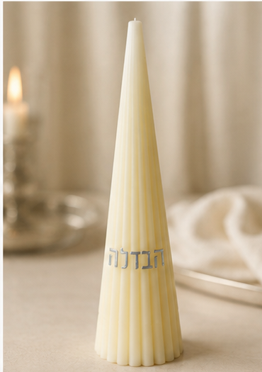 Cream ribbed cone Havdalah candle with silver Hebrew lettering staged on a warm Shabbat table