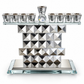 Silver geometric crystal Hanukkah menorah with mirrored pyramid facets and raised central shamash on a white background