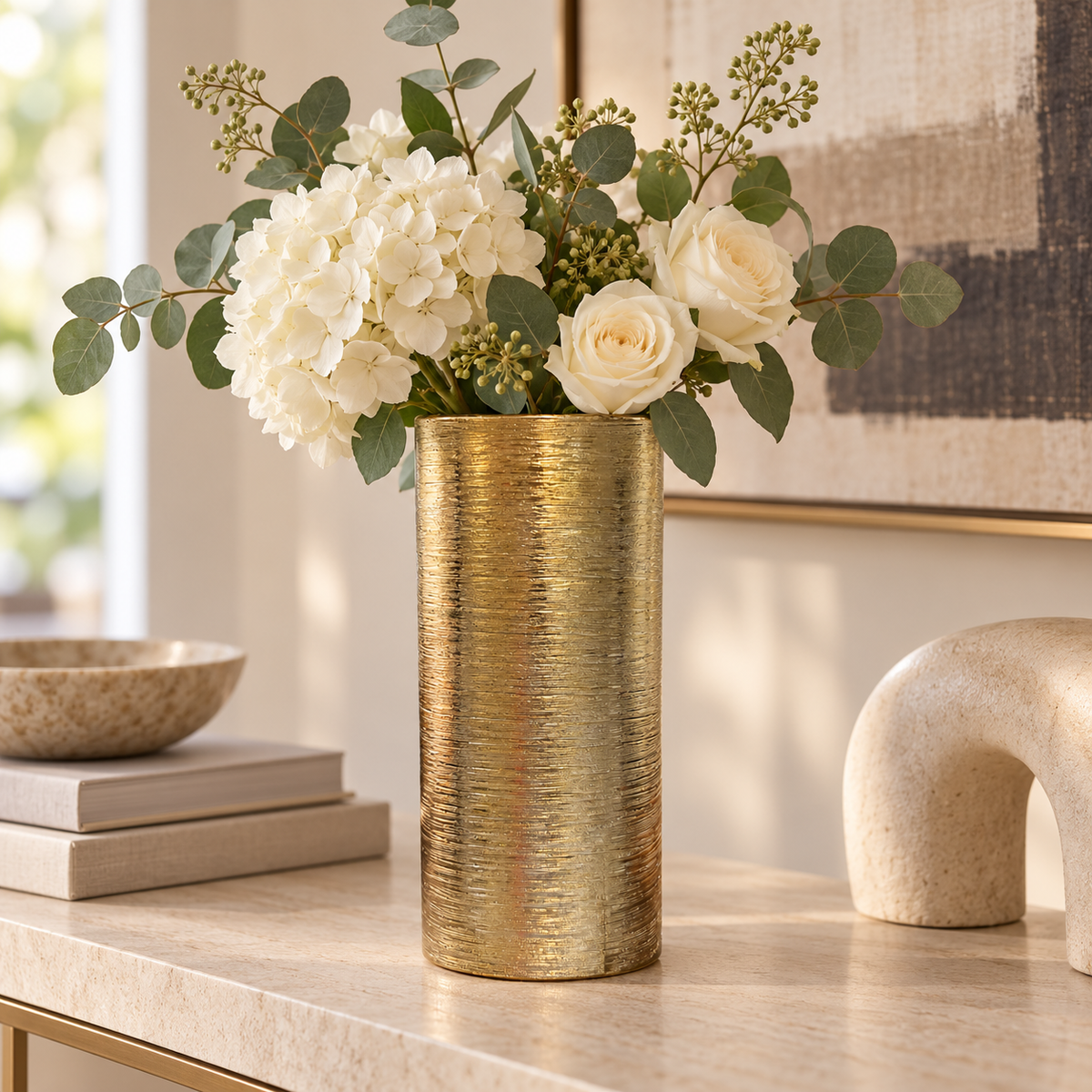 Textured gold ceramic cylinder vase styled with cream flowers and eucalyptus