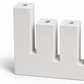 Close-up of white concrete menorah showing raised left shamash, round candle sockets, and rectangular slots