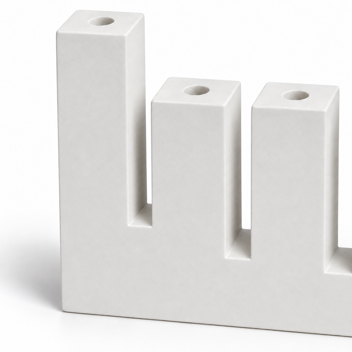 Close-up of white concrete menorah showing raised left shamash, round candle sockets, and rectangular slots
