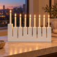 White concrete Hanukkah menorah with nine lit ivory candles on a stone console in a warm modern home