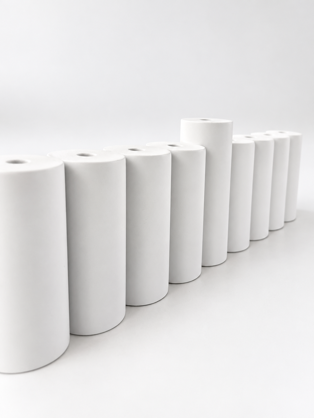 Close-up of matte white concrete menorah cylinders and raised center shamash