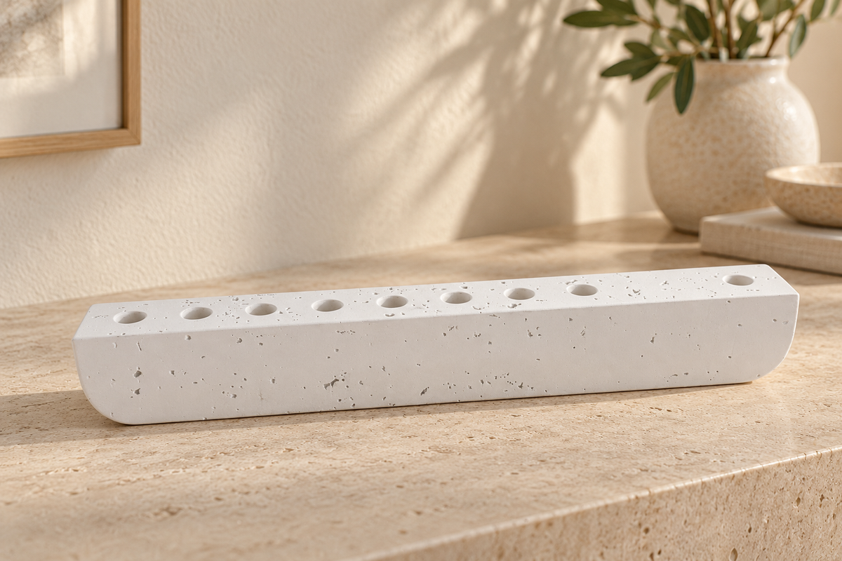 White concrete hanukkiah displayed on a stone console in a softly lit modern home