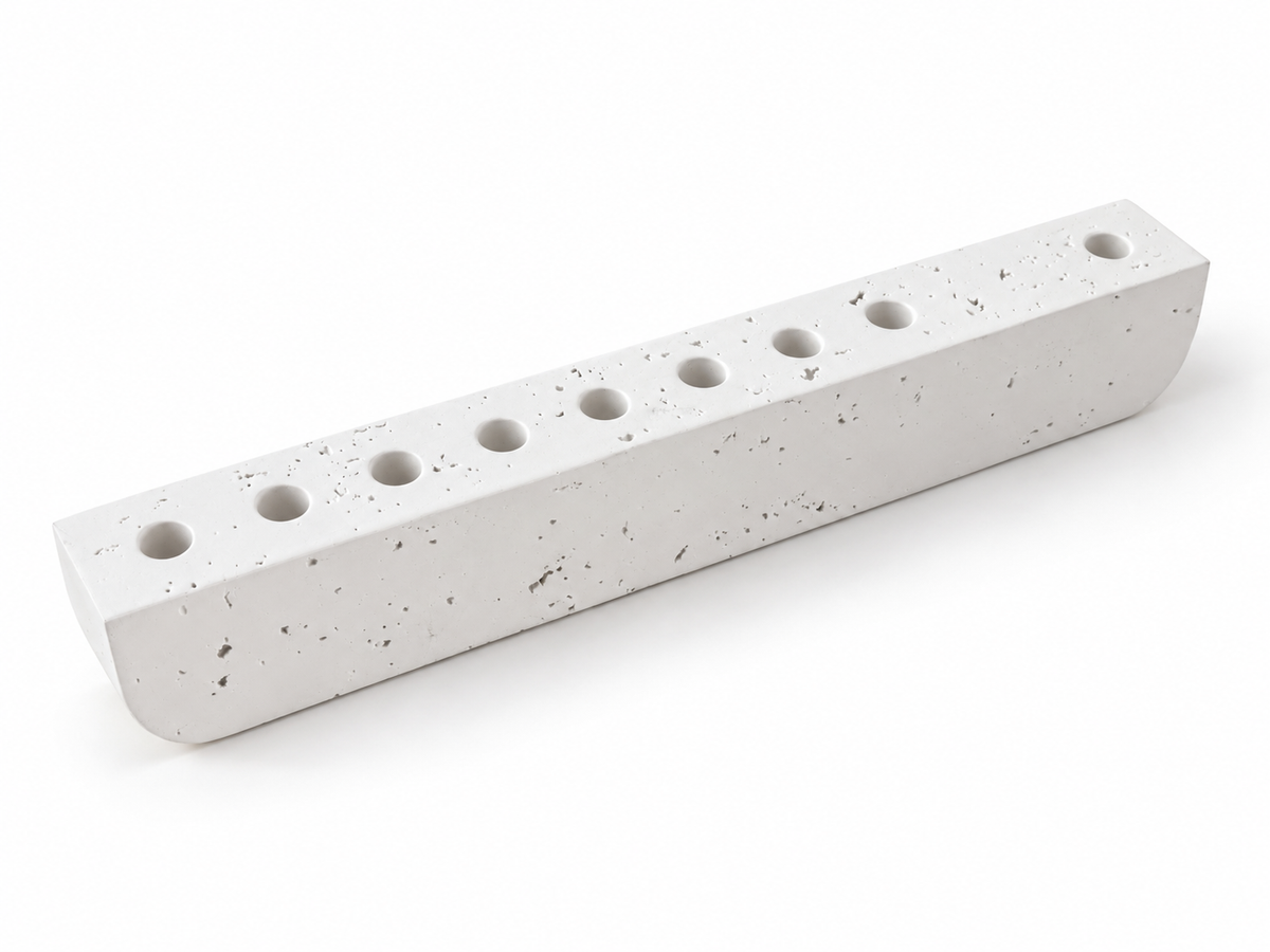 White concrete hanukkiah viewed from above with eight aligned holders and one holder set apart