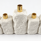 Close-up of the taller center shamash and gold-tone candle holders on the rough white concrete menorah.