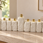 White textured concrete Hanukkah menorah with nine gold-tone holders displayed on a neutral console table.