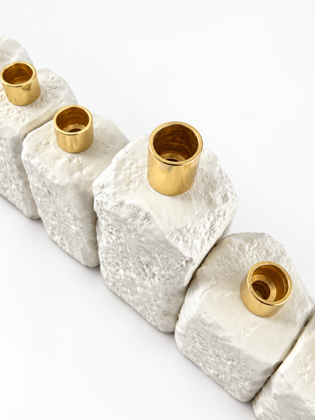 Angled top detail showing open gold-tone candle holders and the rough white concrete texture.
